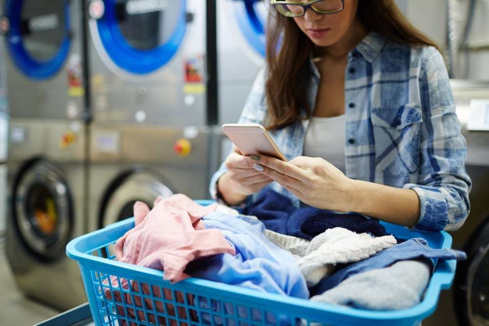 Girl using smartphone while at a laundromat