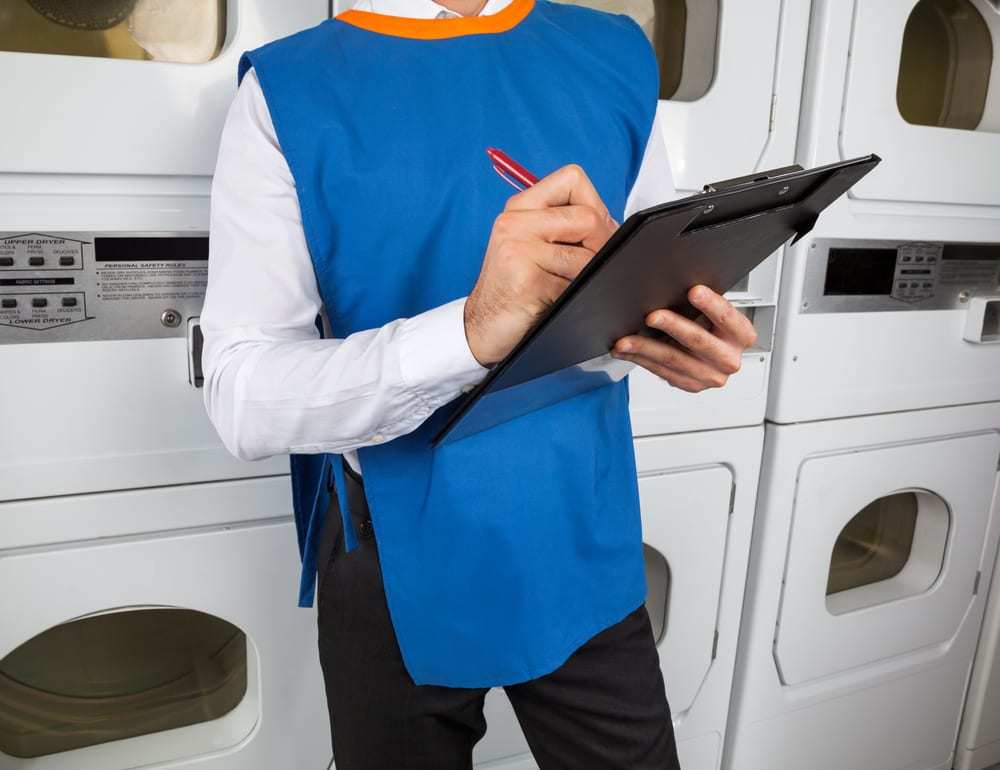 Laundromat manager in blue vest holding clipboard
