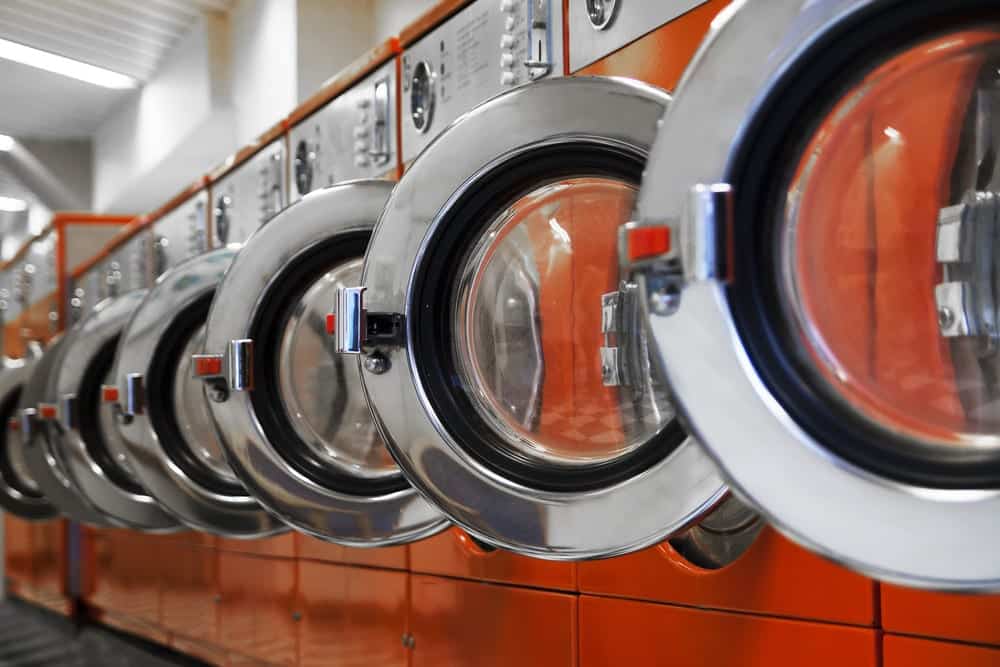 Line of Orange Washing Machines with Doors Open in a Laundromat