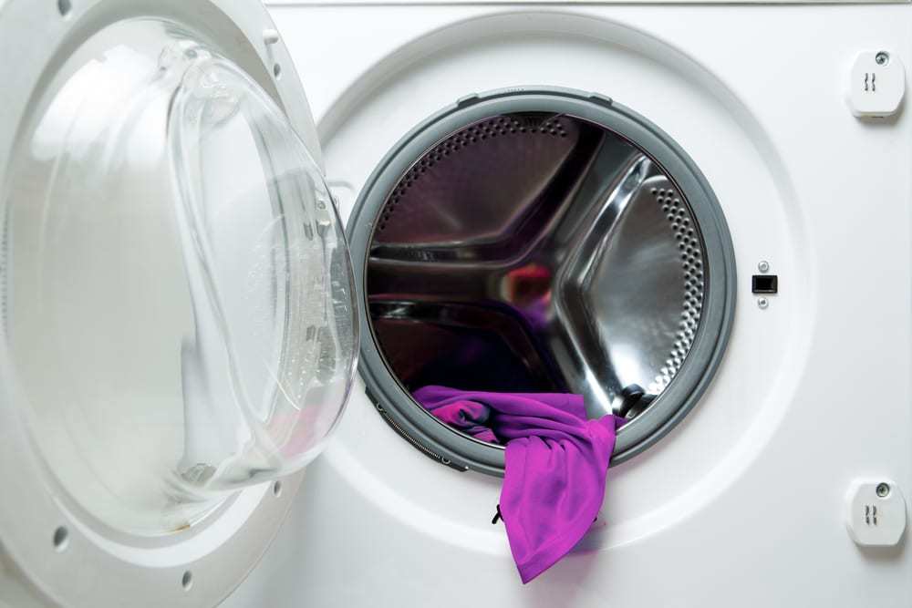 Open washing machine with purple cloth inside