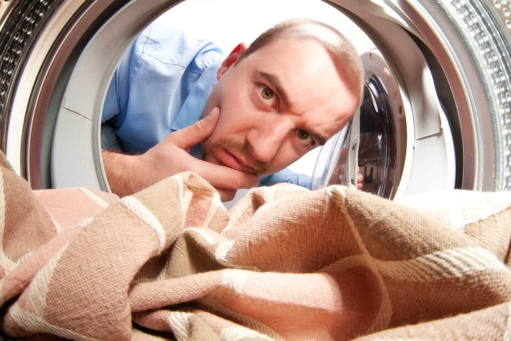 Man Looking Inside Washing Machine with Quizzical Expression