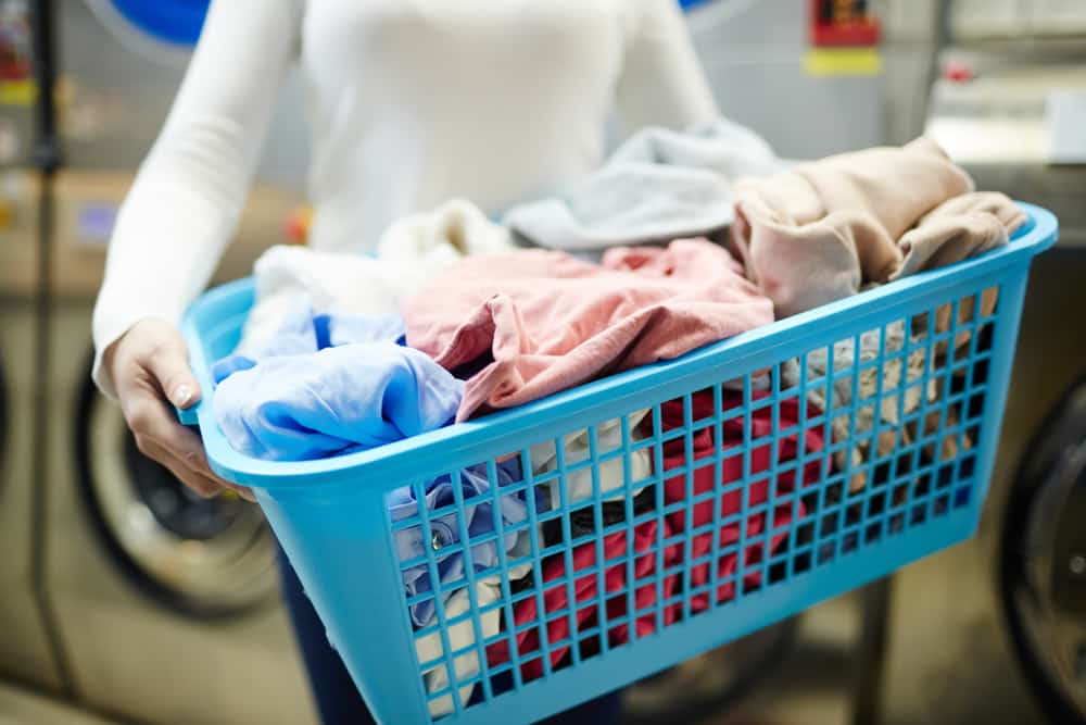 Close-up of woman's arms holding laundry basket in laundromat